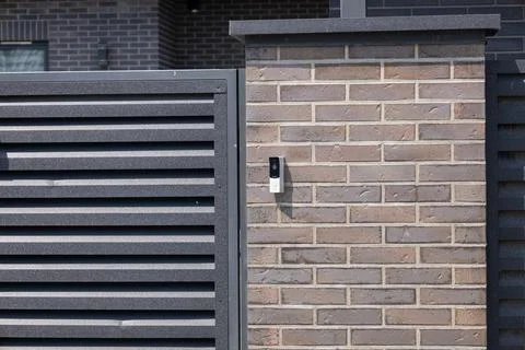 A contemporary intercom system is mounted on a textured brick wall next to .. Stock Photos