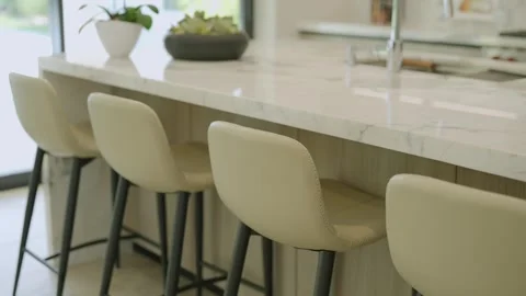 Contemporary kitchen interior with focus on bar counter with several high stools Stock Footage 275825258