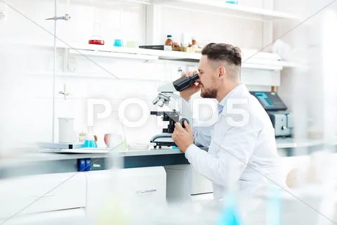 Contemporary scientist working with microscope in scientific laboratory Stock Photos