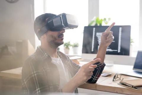 Contemporary software developer in vr headset pointing at virtual display Foto stock
