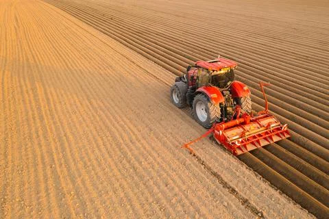 Contemporary tractor drags plug making furrows on soil Stock Photos