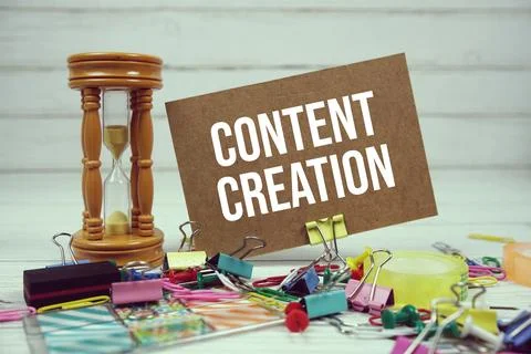 Content Creation text on paper card with alarm clock and stationary on wood.. Stock Photos