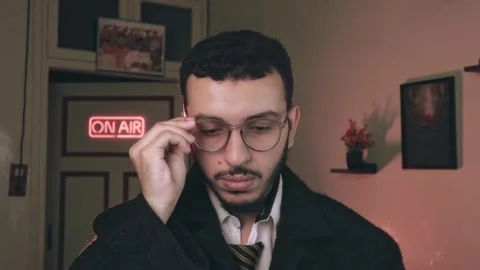 Content Creator Adjusting Glasses in Home Studio with On-Air Neon Sign Video stock 318594158