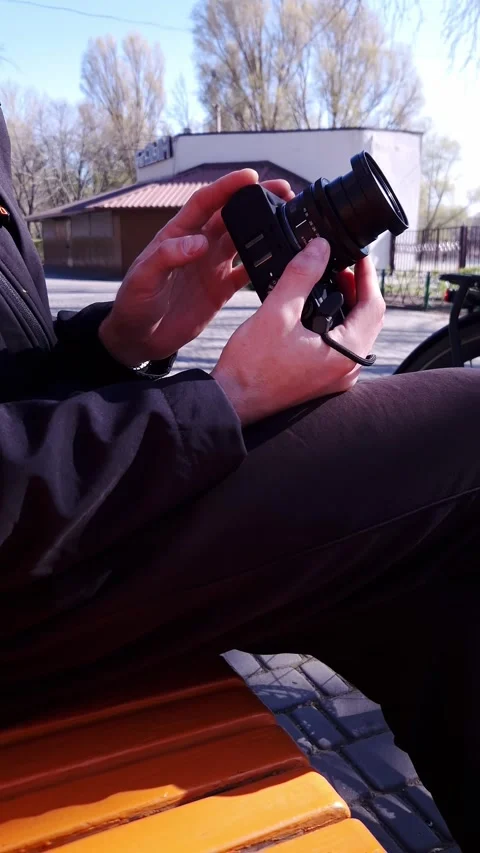 Content Creator Adjusting Mirrorless Device Sitting on Park Bench 스톡 동영상 338999853