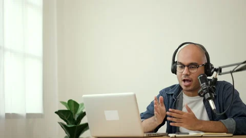Content creator asia man host streaming his a podcast on laptop with headphones. Stock Footage 186391944
