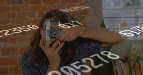 Content creator lifting rangefinder camera as floating numerals guiding framing Stock Footage 314174706