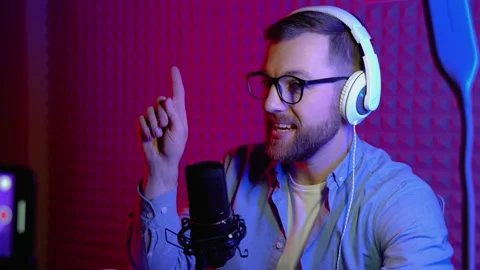 Content creator man host streaming his a podcast on smartphone with headphones Video stock 227346211