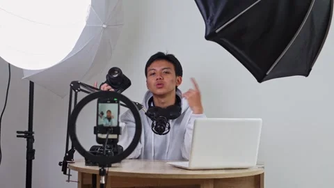 Content creator smiles while filming himself with professional lighting and Stock Footage 337454116