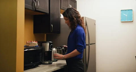 Content female office worker pours coffee smells and drinks it in office kitchen Stock Footage 199458094