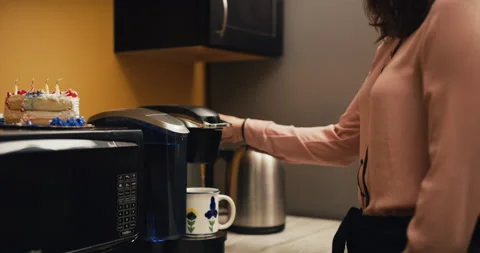Content office worker makes coffee in office kitchen with cake on microwave. Dol Stock Footage 199455515