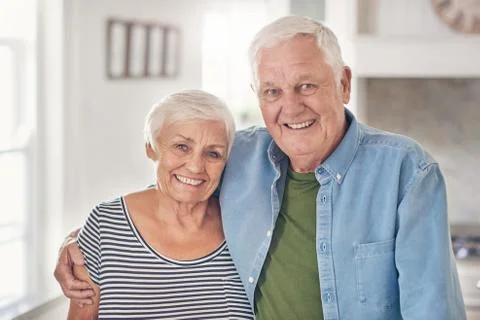Content senior couple standing together at home in their kitchen Stock Photos