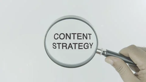Content Strategy text or word highlighted by a magnifying glass in a hand Stock Footage 303605745