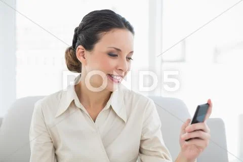 Content stylish brunette businesswoman looking at her mobile phone Stock Photos