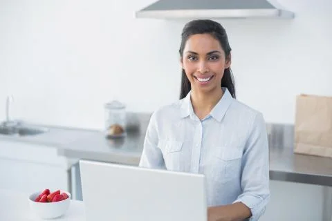 Content woman using her notebook standing in bright kitchen Stock Photos