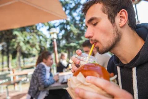 Contented guy is drinking his fruit juice, his eyes are closed. He is holding Stock Photos