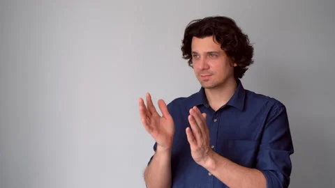 Contented interested man clapping hands on gray background with copy space. Stock Footage 311875878