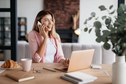 Contented lady having phonecall while working from home Stock Photos