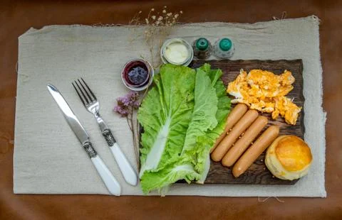 Continental breakfast with scrambled eggs, fried sausages, vegetable and scon Stock Photos
