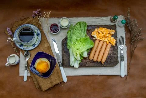 Continental breakfast with scrambled eggs, fried sausages, vegetable and scon Stock Photos