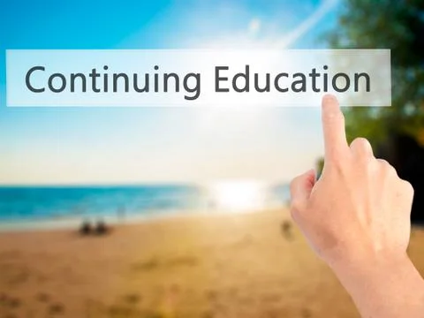 Continuing Education - Hand pressing a button on blurred background concept o Stock Photos
