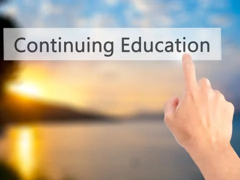 Continuing Education - Hand pressing a button on blurred background concept o Stock Photos
