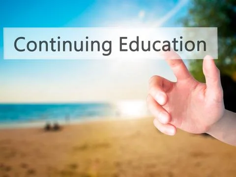 Continuing Education - Hand pressing a button on blurred background concept o Stock Photos