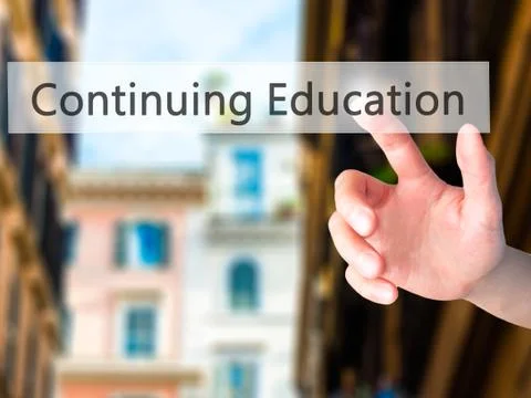 Continuing Education - Hand pressing a button on blurred background concept o Stock Photos