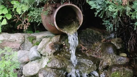 A continuous flow of refreshing water pours from a clay pot, cascading over Vídeos de archivo 329374385