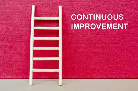CONTINUOUS IMPROVEMENT on red background with a ladder symbolizing continuo.. Stock Photos
