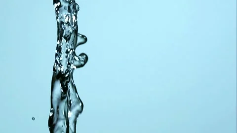A continuous stream of clear water pours down against a light blue background Stock Footage 326628881