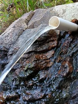 Continuous water stream. Spring flowing through water tube. Foto stock
