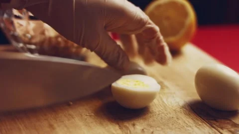Contour effect of Cut boiled eggs into rings with a knife on a wooden board Stock Footage 240632545