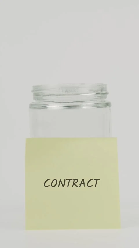 Contract text or word on yellow sticky note attached to glass jar with hand Stock Footage 311698198