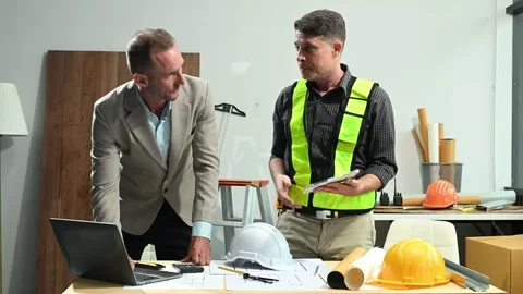 Contractor and architect looking at plan, tablet, laptop and talking about .. Stock Footage 313705772