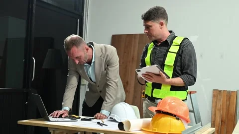 Contractor and architect looking at plan, tablet, laptop and talking about .. Stock Footage 313705774