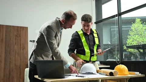 Contractor and architect looking at plan, tablet, laptop and talking about .. Stock Footage 313705782