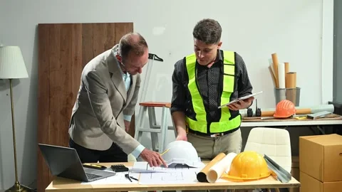 Contractor and architect looking at plan, tablet, laptop and talking about .. Stock Footage 313705783
