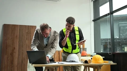 Contractor and architect looking at plan, tablet, laptop and talking about .. Stock Footage 313705814