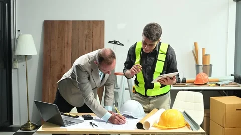 Contractor and architect looking at plan, tablet, laptop and talking about .. Stock Footage 313705822