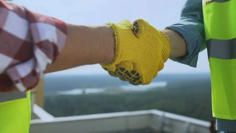 Contractor and builder in uniform shaking hands on roof, work cooperation, deal Stock-Footage 117195667