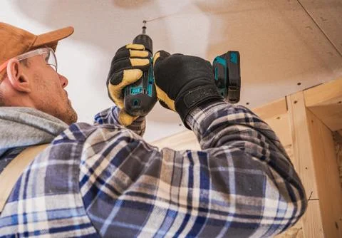 Contractor Assembling Drywall Board Using Drill Driver Foto stock