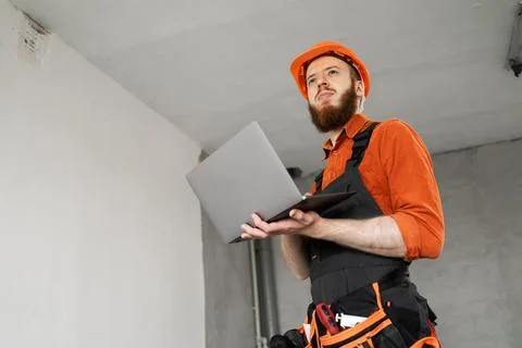 Contractor builder in hardhat and uniform using computer. Building and home.. Stock Photos