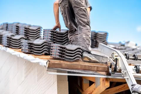 Contractor builder laying fired ceramic tiles on the roof Stock Photos