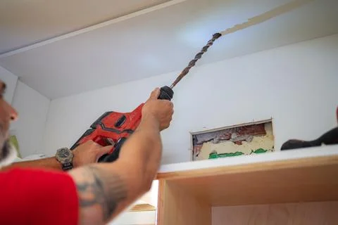 Contractor drilling a hole in the ceiling using a hammer drill Stock Photos