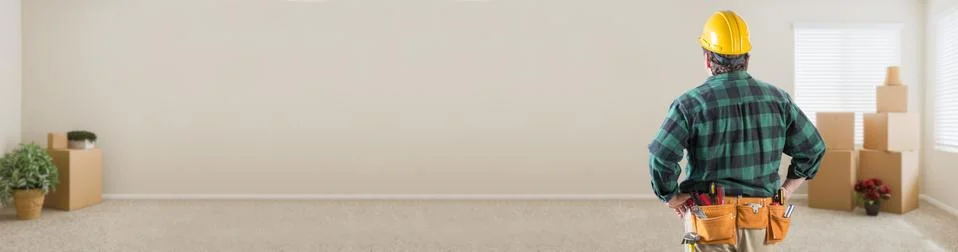 Contractor in Hard Hat Looking at Blank Wall in Empty Room with Moving Boxes  Stock Photos