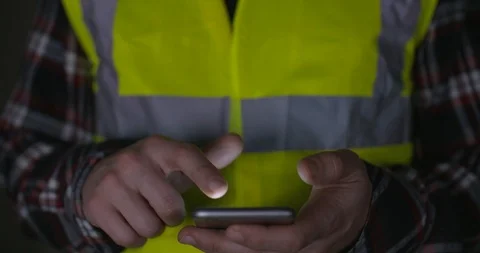 Contractor in hi-vis vest scrolling on smart phone touch screen. 4k Slow motion. Vídeos de archivo 89853320