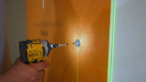Contractor installing waterproof membrane on a bathroom wall using a drill Stock Footage 346801927
