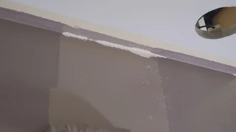 Contractor paints wall with roller brush near room ceiling Stock Footage 124892598