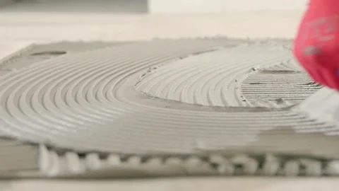 Contractor spreading tile adhesive on the floor before installing tiles. Tiler Stock Footage 344030467
