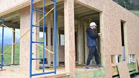 Contractor takes measurements in timber frame house under construction Stock Footage 346767762